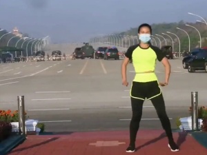 [video] Kobieta prowadzi transmisję aerobiku w Birmie, nie widząc za plecami konwoju jadącego na parlament. Film podbija internet