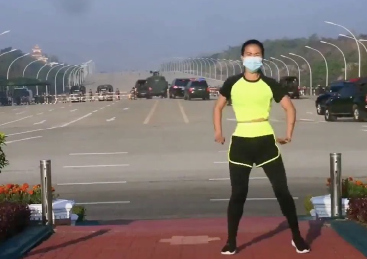  [video] Kobieta prowadzi transmisję aerobiku w Birmie, nie widząc za plecami konwoju jadącego na parlament. Film podbija internet