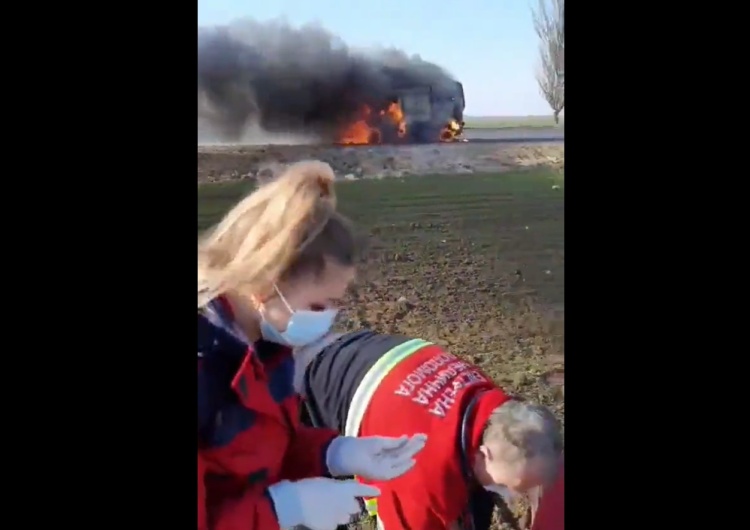 Ratownicy medyczni usiłują pomoc rannemu. W tle płonie karetka Wstrząsające nagranie. Rosjanie mieli zaatakować karetkę z rannymi [VIDEO 18+]