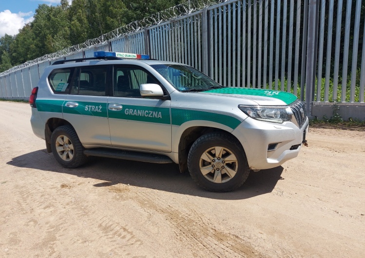 Samochód Straży Granicznej przy barierze na granicy z Białorusią Straż Graniczna montuje elementy bariery elektronicznej na granicy z Białorusią. Podaje daty [WIDEO]